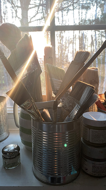 Morning light shining through a studio window filled with brushes