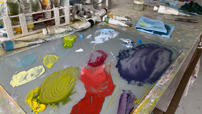 Painter's mixing palette with oil paint with tubes of oil paint scattered behind it